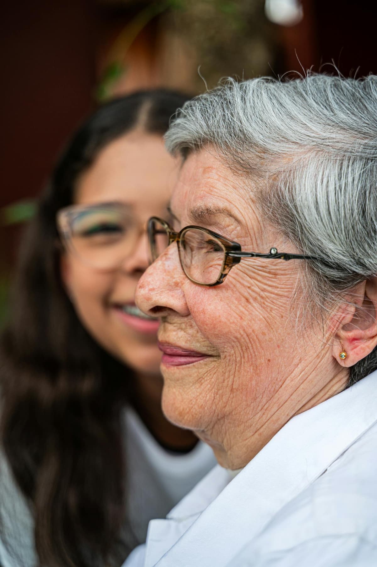 Caregiver helping elderly woman walk with mobility walker at home